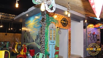 A restaurant with a mural of a cityscape, a brick wall, and a sign that reads "DOWN THE LANE."