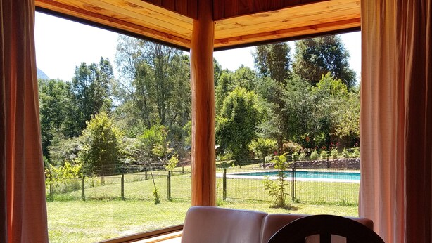 Una cabaña de madera con vista a una piscina y un patio cercado.