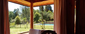 A wooden cabin with a view of a swimming pool and a fenced yard. - Traumaco Lodge (Pucón)