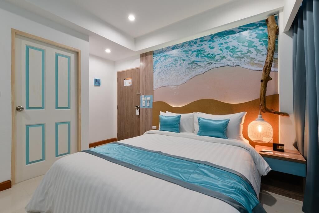A hotel room with a bed, a nightstand, a wall mural, and a door.