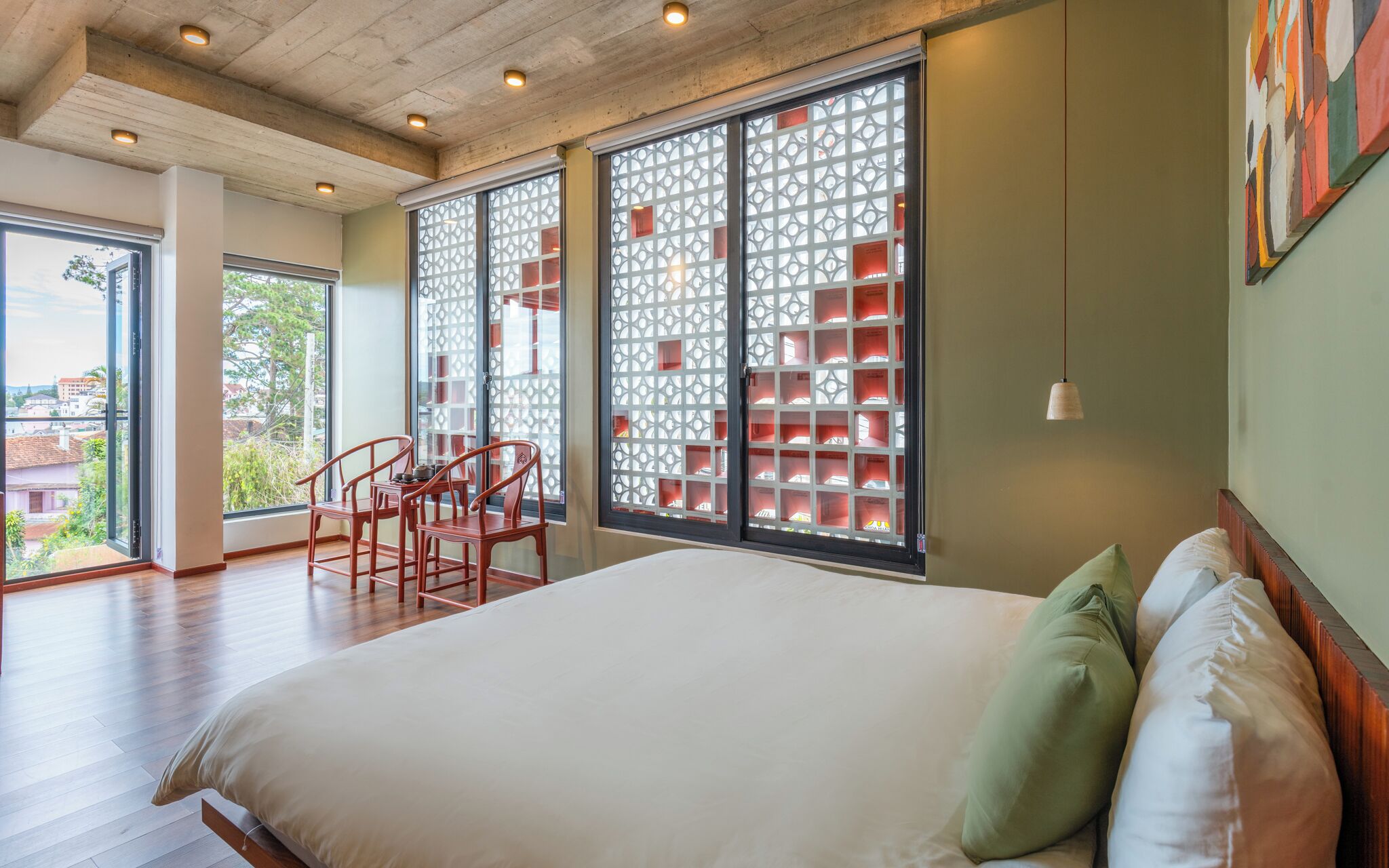 A bedroom with a large bed, two chairs, a table, and a decorative screen.