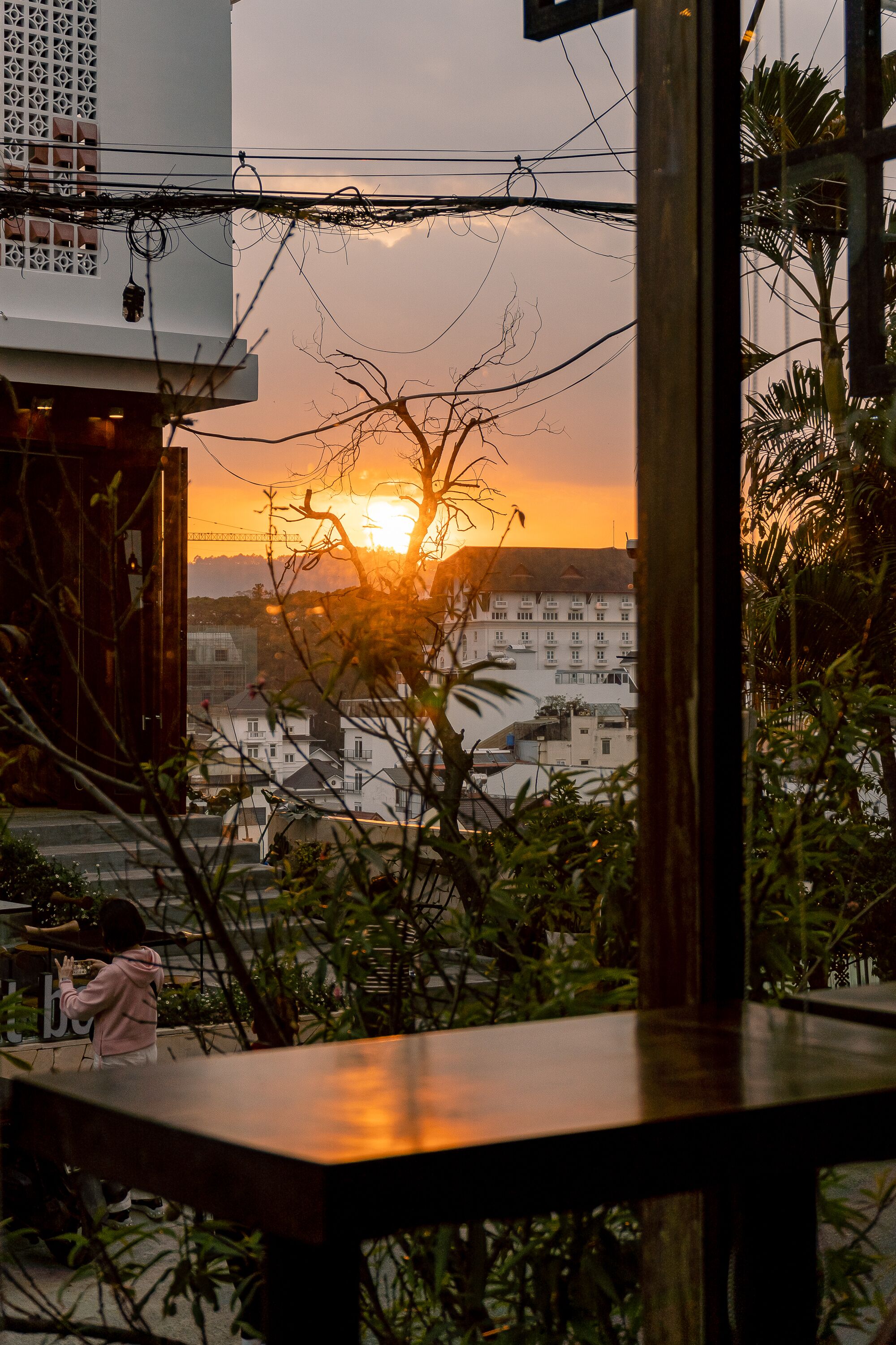 A sunset view from a balcony with a table in the foreground and a person standing nearby.