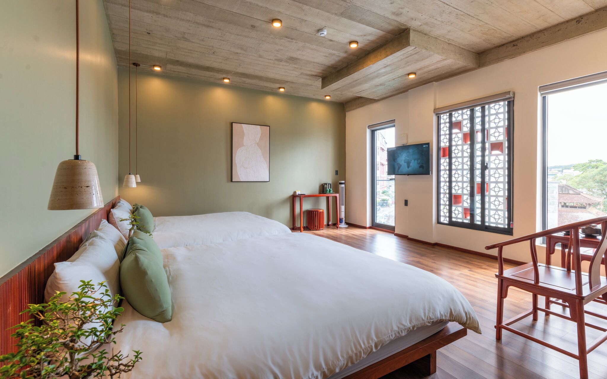 A spacious bedroom with a large bed, a wooden headboard, a small table, a TV, and a large window with a view.