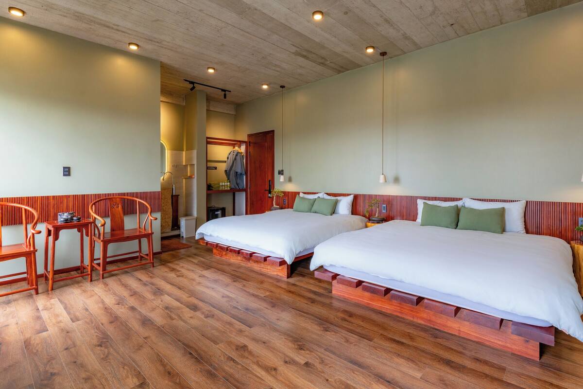 Une chambre d’hôtel avec deux lits, un plancher en bois et un coin salon avec des chaises.