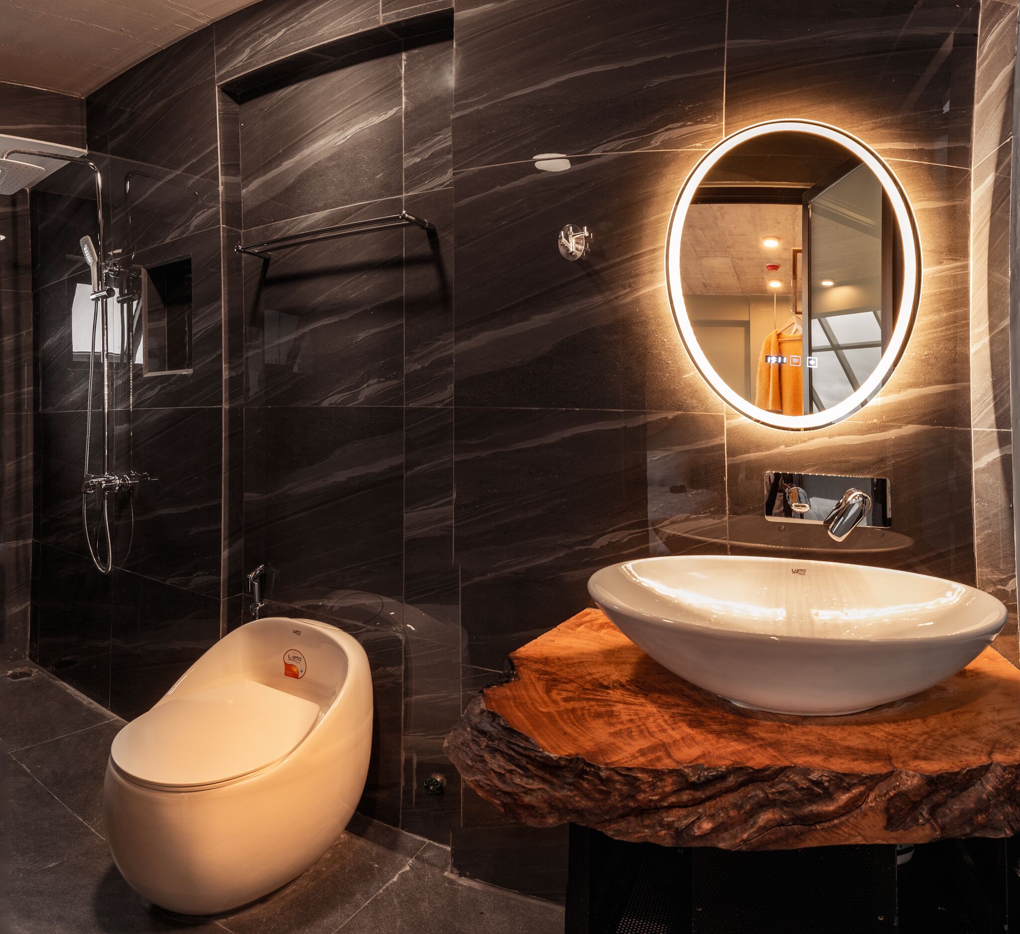A modern bathroom with a bidet, a round mirror, and a marble countertop.