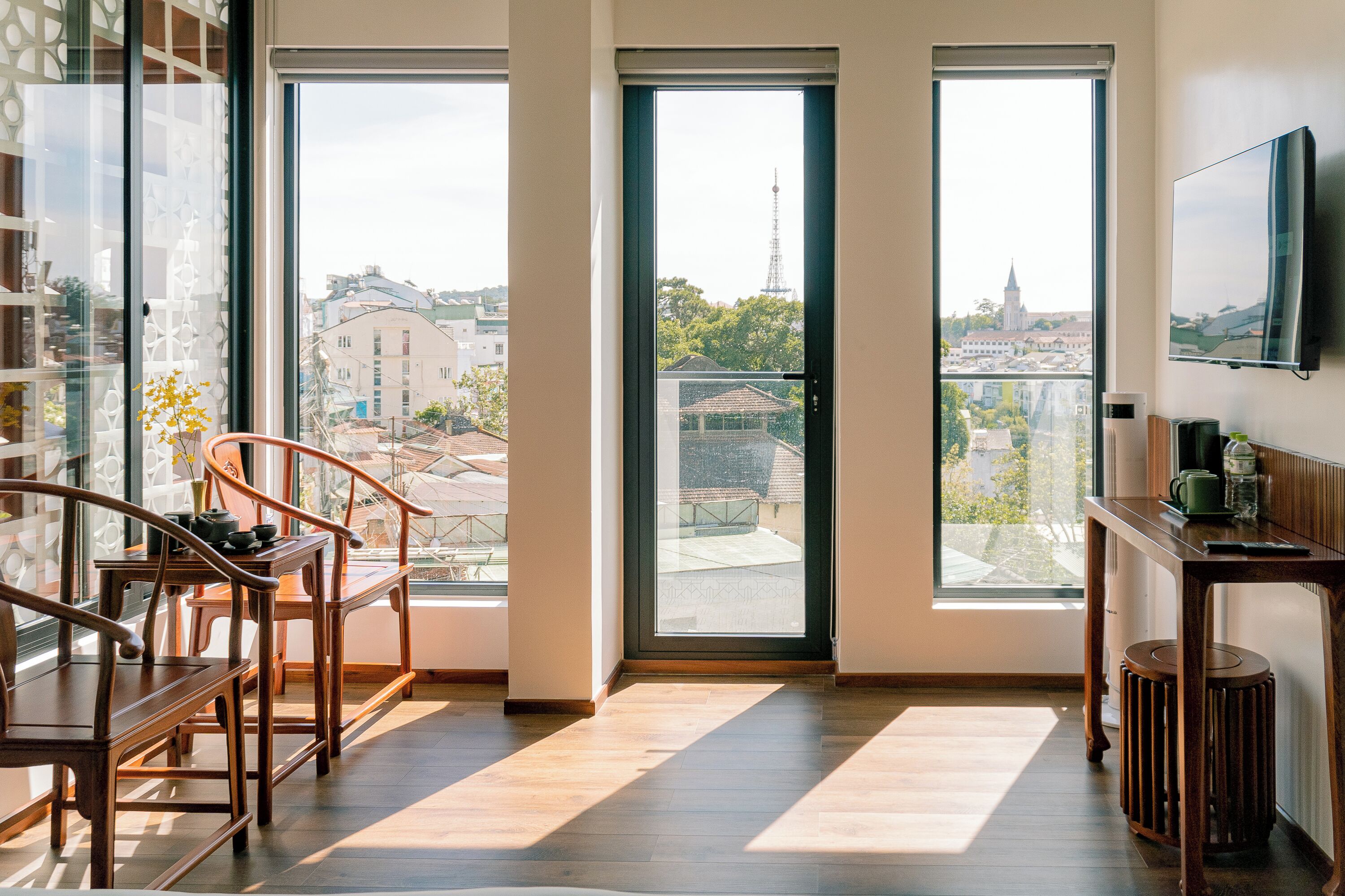 Une chambre moderne avec de grandes fenêtres, un plancher en bois et une vue sur le paysage urbain.