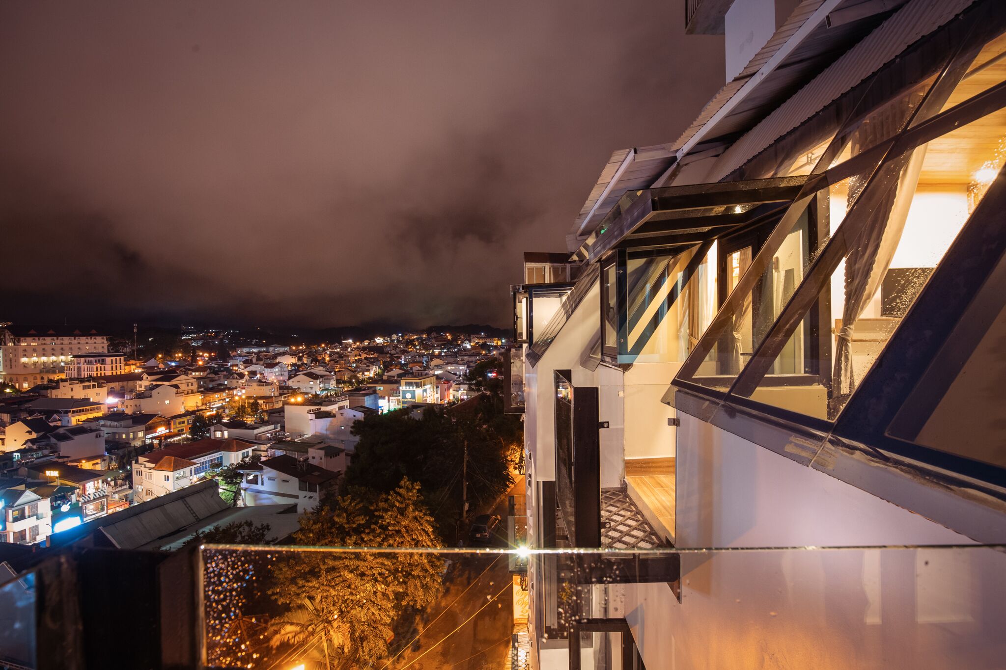 Panoramica notturna di una città con vista su un edificio moderno dotato di ampie finestre e un balcone.