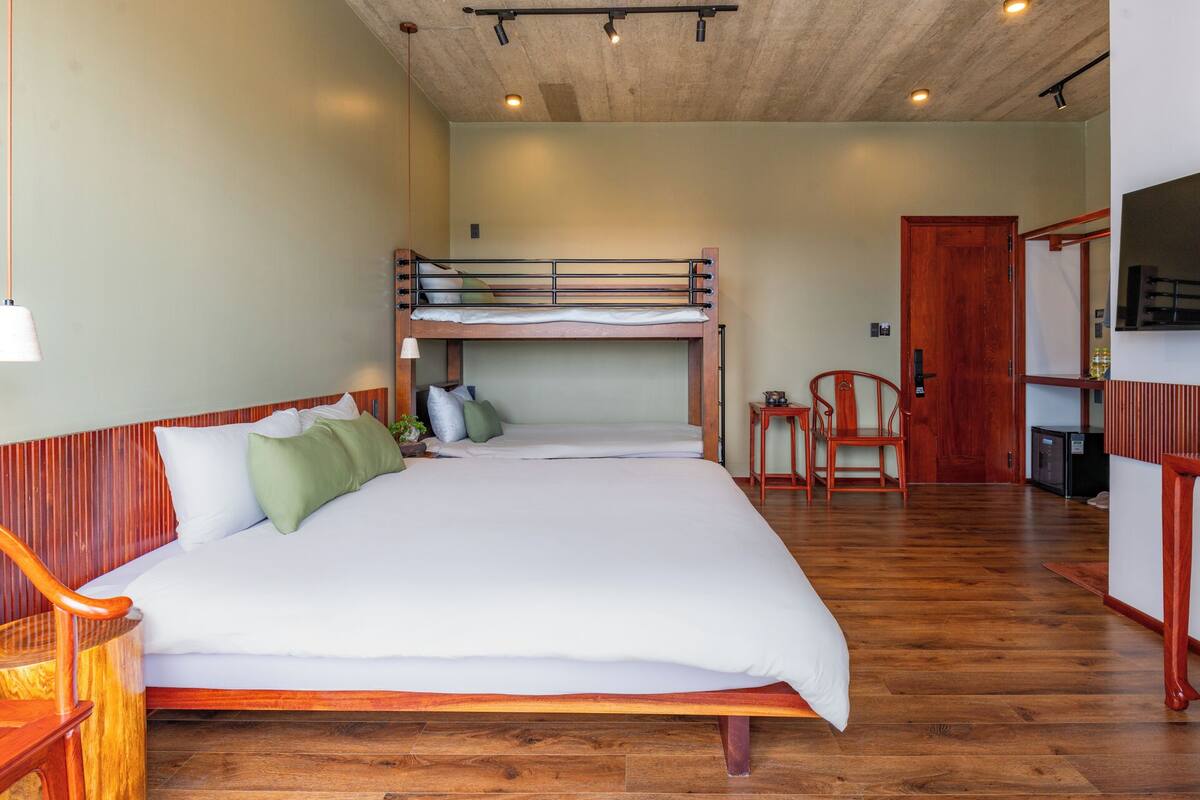 Une chambre avec un lit superposé, un bureau en bois, une chaise et un téléviseur.