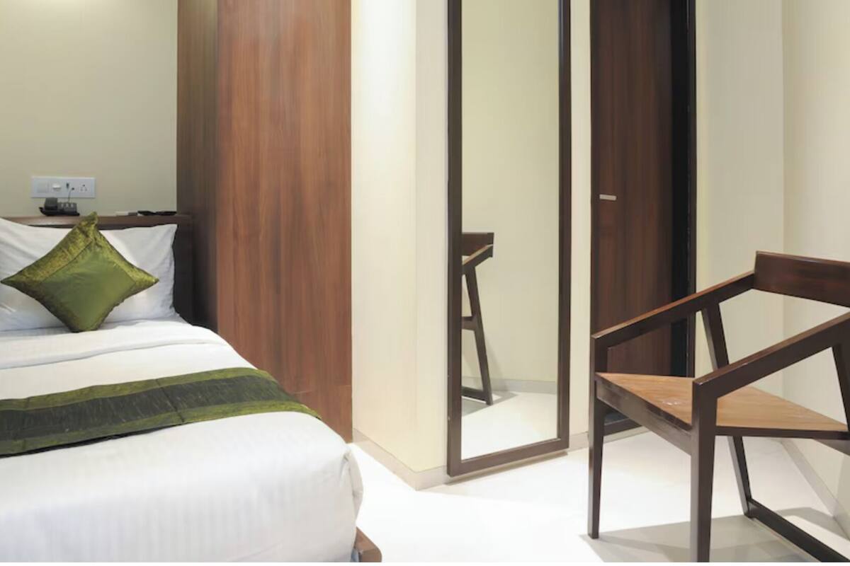Une chambre d’hôtel avec un lit, une chaise en bois et une armoire.
