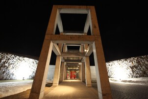 Una entrada de edificio moderna con una estructura geométrica y una puerta roja.