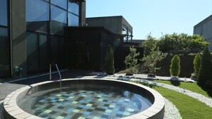 Un bâtiment moderne doté d’une piscine circulaire, bordée de galets et entourée d’une pelouse bien entretenue.