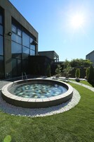 Un edificio moderno con una piscina circular bordeada de piedras y un césped bien cuidado.