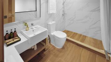 Une salle de bain moderne avec un lavabo, des toilettes et une douche, le tout de couleur blanche.
