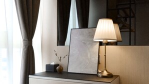 A neatly arranged bedside table with a lamp, a framed picture, and a vase with branches. - Eco Tree Hotel Causeway Bay (Hong Kong)