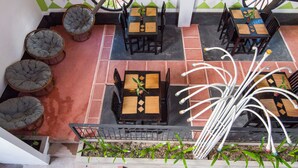 A rooftop terrace with multiple dining tables and chairs, surrounded by potted plants and decorative elements. - Golden Ganesha Villa - Hostel (Siem Reap)