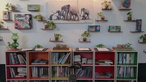 A library with bookshelves and a painting of elephants on the wall. - Golden Ganesha Villa - Hostel (Siem Reap)