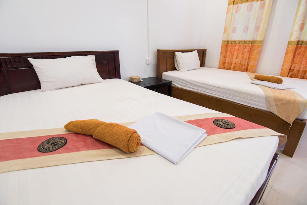 Habitació d'hotel amb dos llits, cadascun amb capçalera de fusta, roba de llit blanca i una tovallola decorativa.