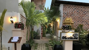 A hotel entrance with a brick facade, a signboard, and potted plants. - Golden Ganesha Villa - Hostel (Siem Reap)