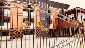 A gated entrance with decorative golden lion statues. - Thana Apartment (Si Racha)