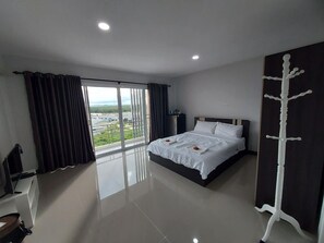 Habitación de hotel con una cama grande, vistas al exterior, un televisor de pantalla plana y un perchero.