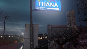 A sign for Thana with contact numbers and an arrow pointing right. - Thana Apartment (Si Racha)