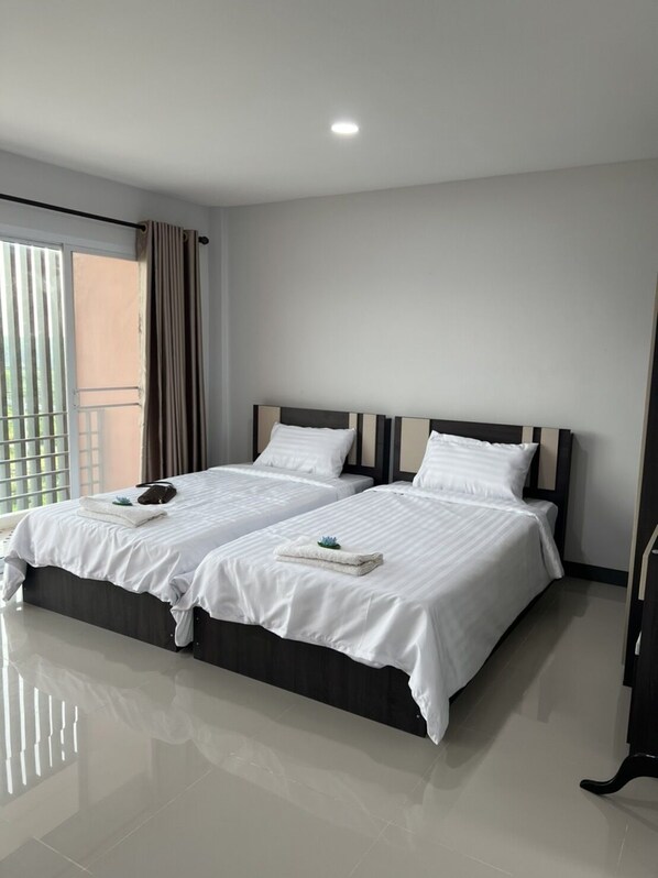 Habitación de hotel con dos camas, un ventanal grande con persianas y una lámpara en el techo.