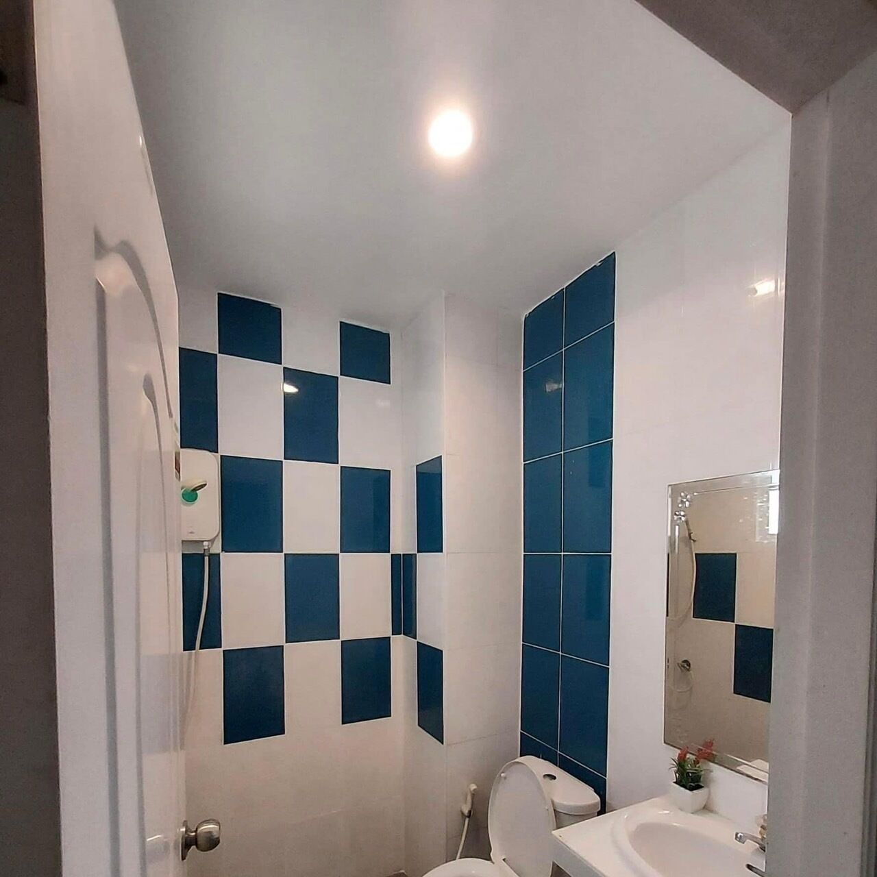 A bathroom with blue and white checkered tiles, a white toilet, and a sink with a mirror above it.
