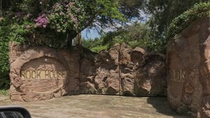 Fachada de roca con la inscripción "Rock House" y un área de entrada pavimentada.