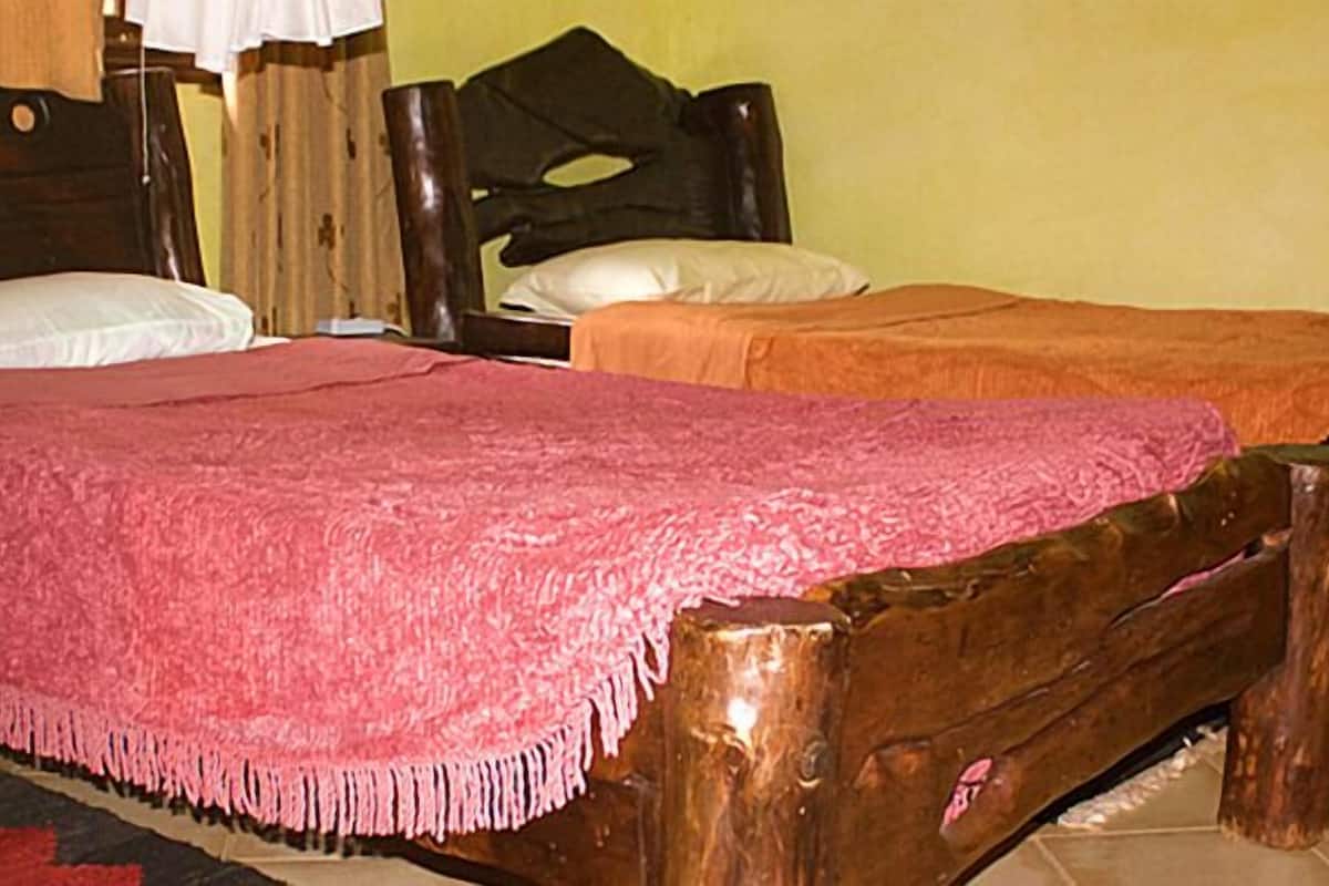 Ein Zimmer mit zwei Holzbett, eines mit einer rosa Decke, das andere mit einer orangefarbenen.