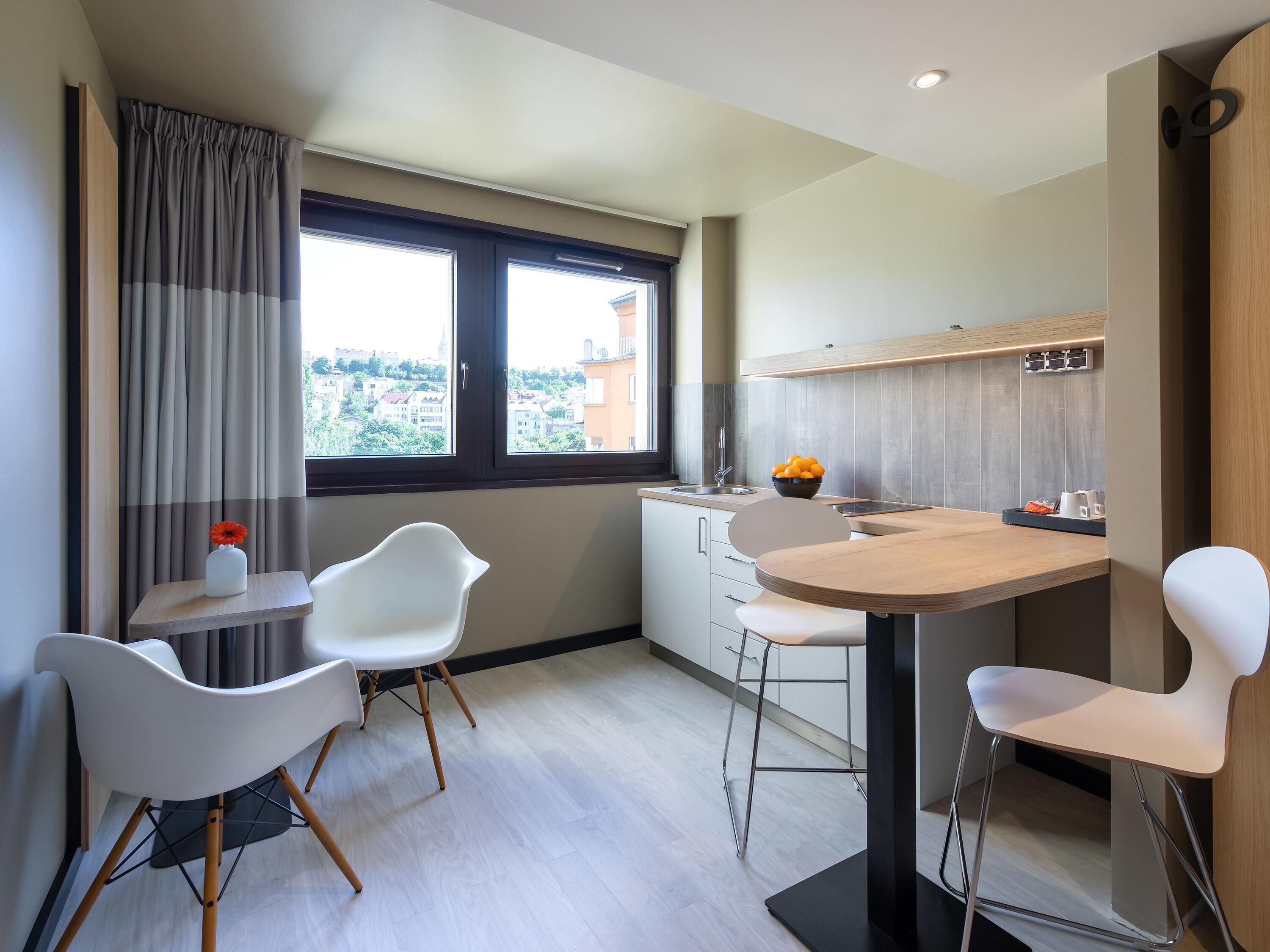 Cozinha moderna com área de refeições, janela com vista e pequena mesa com cadeiras.