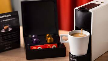 Una cafetera con una taza de café, una caja de cápsulas de café y una cafetera Krups.