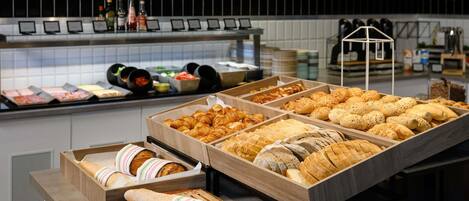 Una vitrina de panadería con diversos tipos de pan y pasteles.