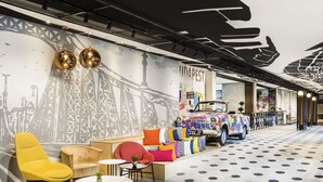 Un interior moderno con un mural que muestra un puente, un coche antiguo y una zona de estar con mesas y sillas.