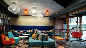 A modern lounge area with a blue sofa, colorful chairs, and a red hanging chair. - Tru By Hilton Staunton (Staunton)