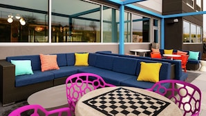 An outdoor seating area with a blue sofa, colorful cushions, and a checkered table. - Tru By Hilton Staunton (Staunton)