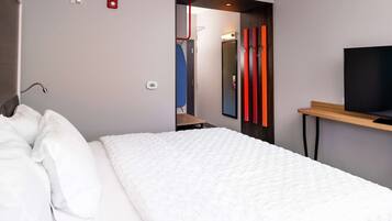 Ein modernes Hotelzimmer mit einem großen Bett, einem Fernseher auf einem Holzboden und einem Spiegel an der Wand.