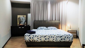 A bedroom with a bed, a nightstand, a lamp, and a painting on the wall. - PJ8 Service Suite Pool View (Petaling Jaya)