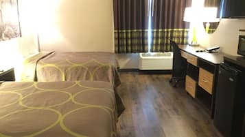 Habitación de hotel con dos camas, un escritorio, una silla, un televisor y un equipo de aire acondicionado.