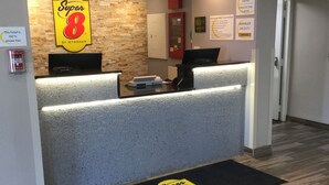 Ein Hotel-Empfangsbereich mit Steinwand, Empfangstresen und Hinweisschild für Check-in/Check-out.