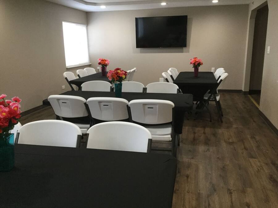 A conference room with white chairs, black tables, and flower vases.