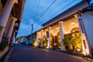 A street view of a building with a covered entrance, columns, and potted plants. - Muhsin Villa (Galle)