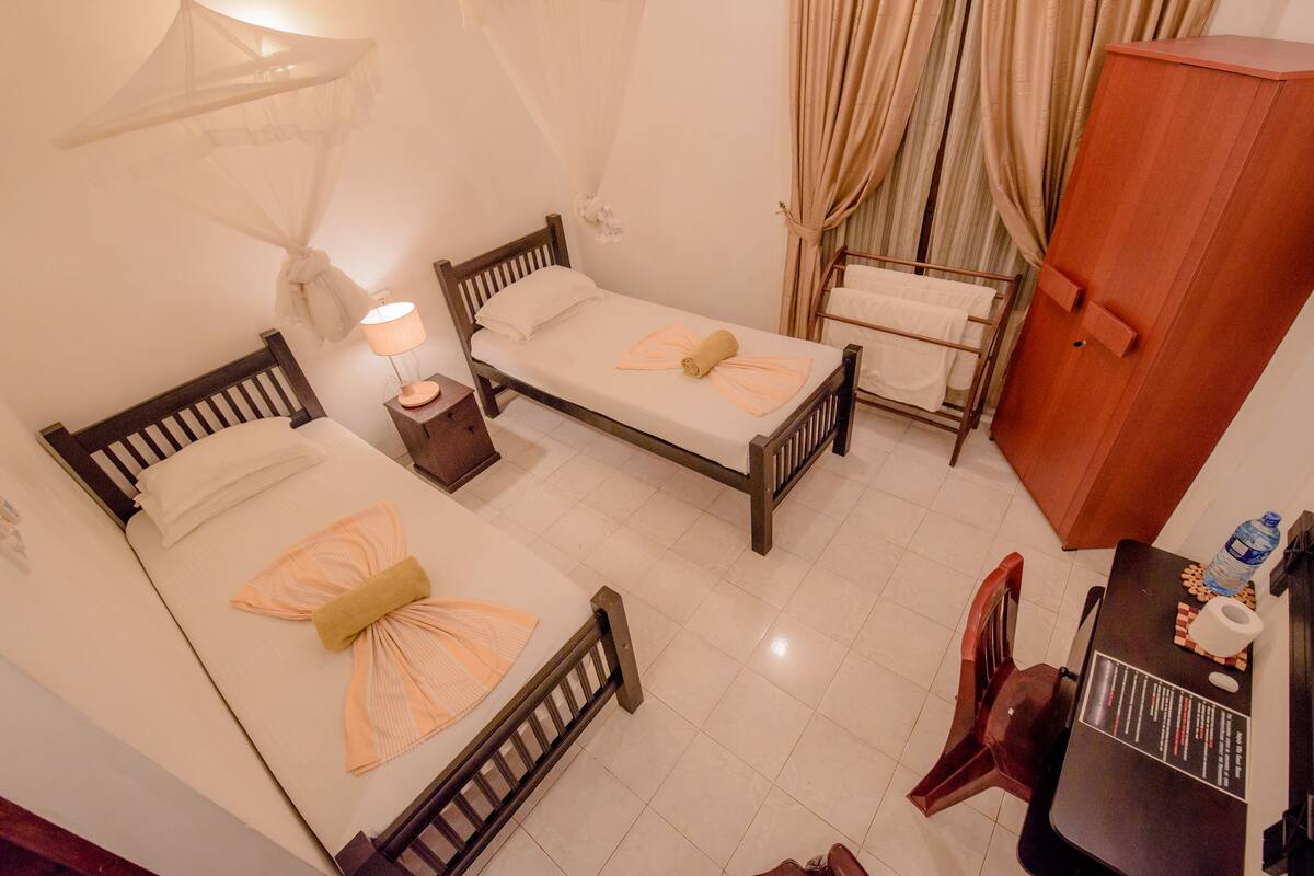 A room with two beds, a desk, a chair, and a wardrobe.