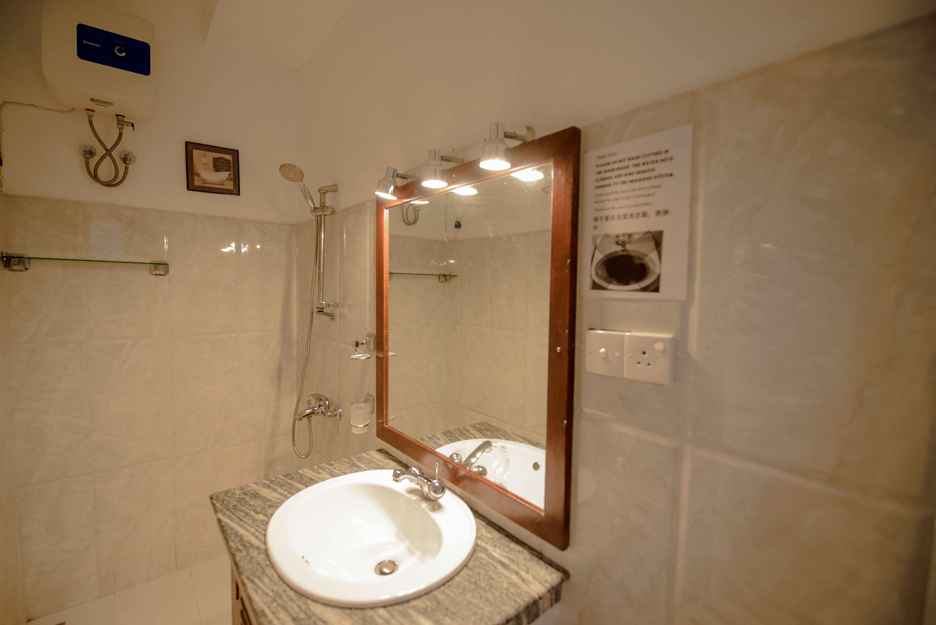 Une salle de bain équipée d’un lavabo, d’un miroir, d’une douche et d’un porte-serviettes.