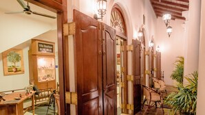 Um corredor com portas de madeira, um ventilador de teto e um vaso com planta.
