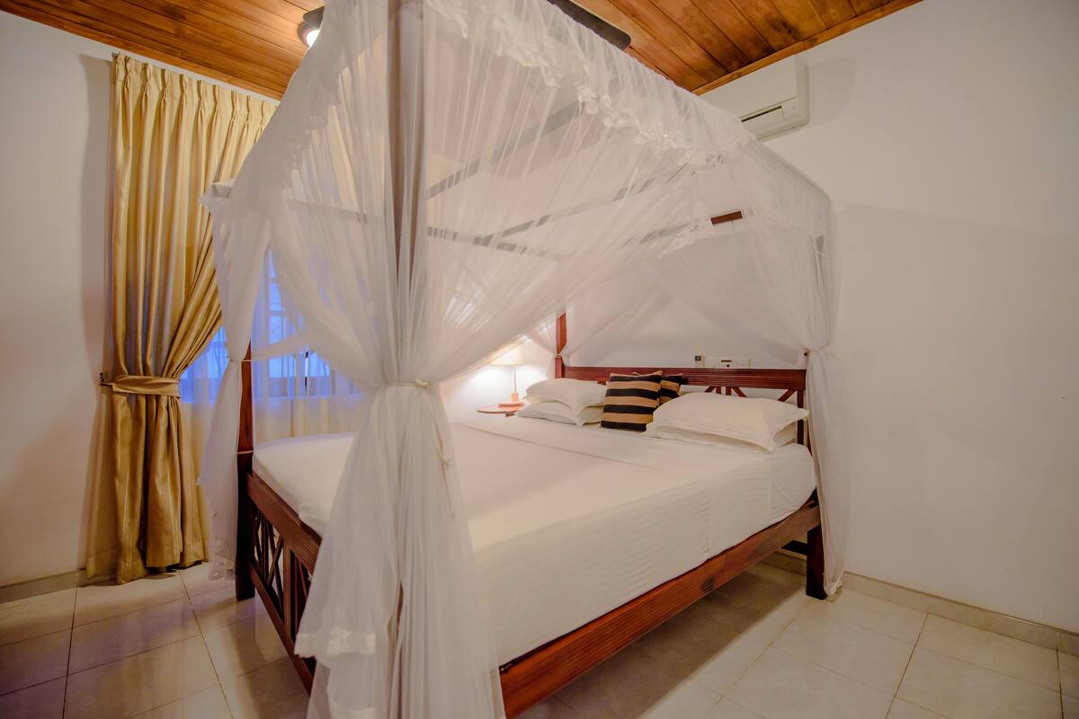 A bedroom with a four-poster bed, a wooden headboard, and a canopy.