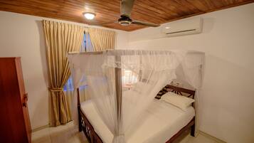 A bedroom with a four-poster bed, wooden ceiling, beige curtains, and an air conditioning unit.