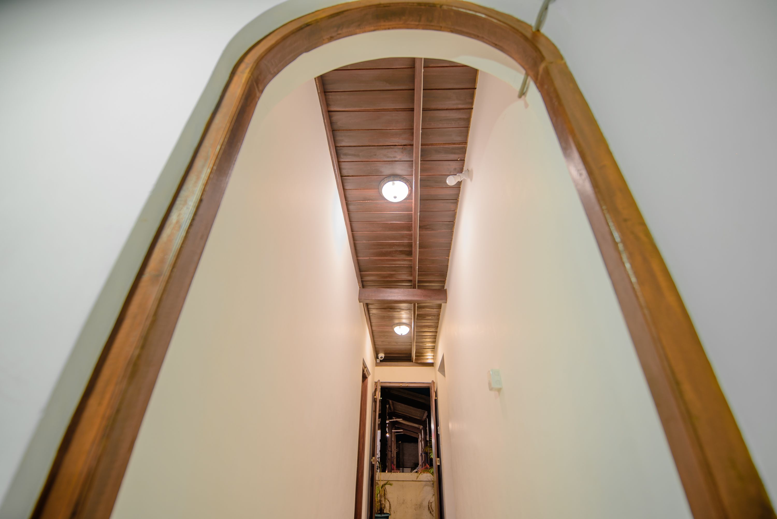 A narrow hallway with a wooden ceiling and a circular light fixture.