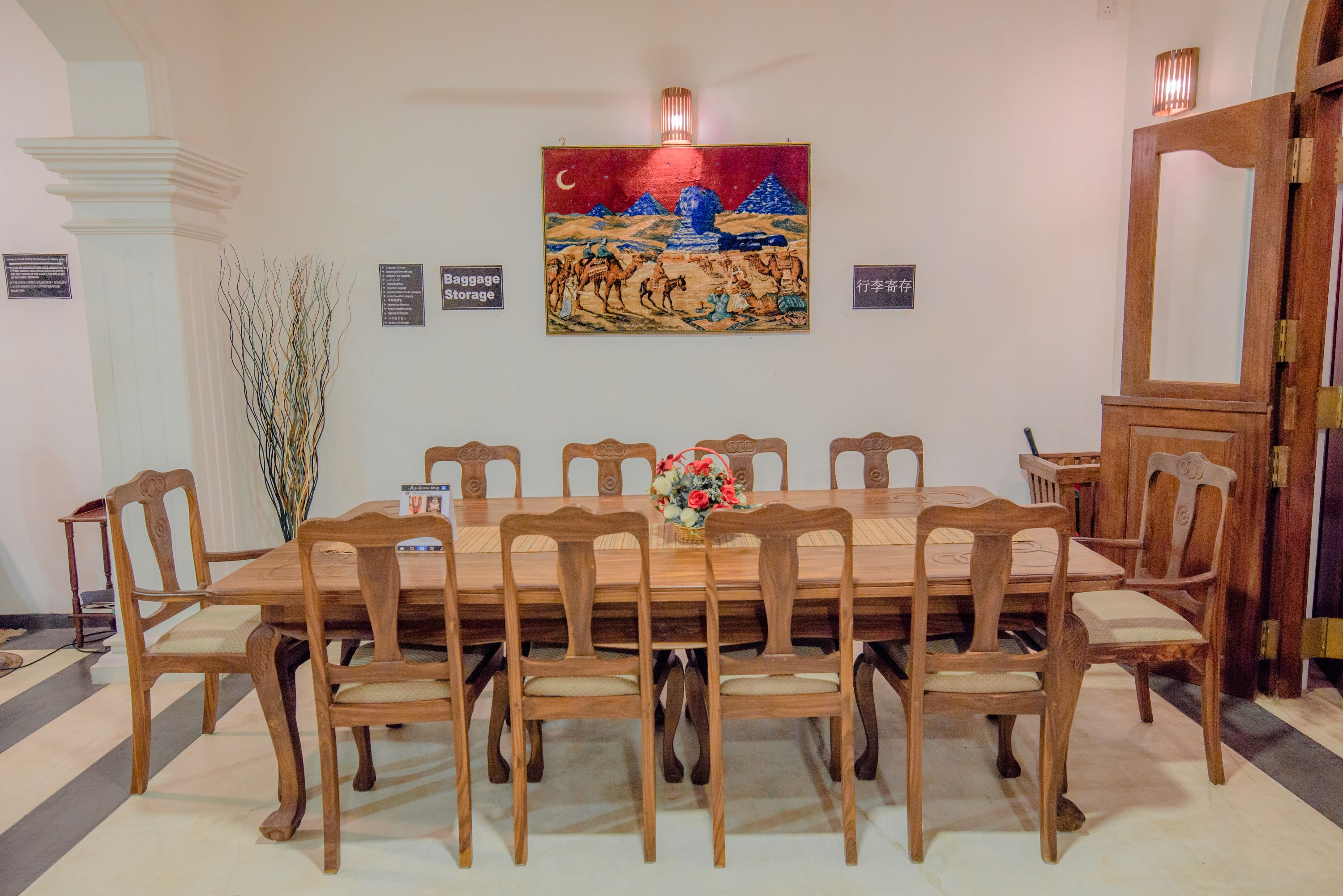 Un comedor con una mesa y sillas de madera, un jarrón de flores y un cuadro en la pared.