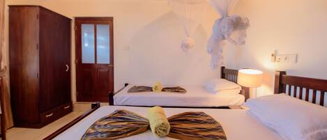 A hotel room with two beds, a wardrobe, and a mosquito net.