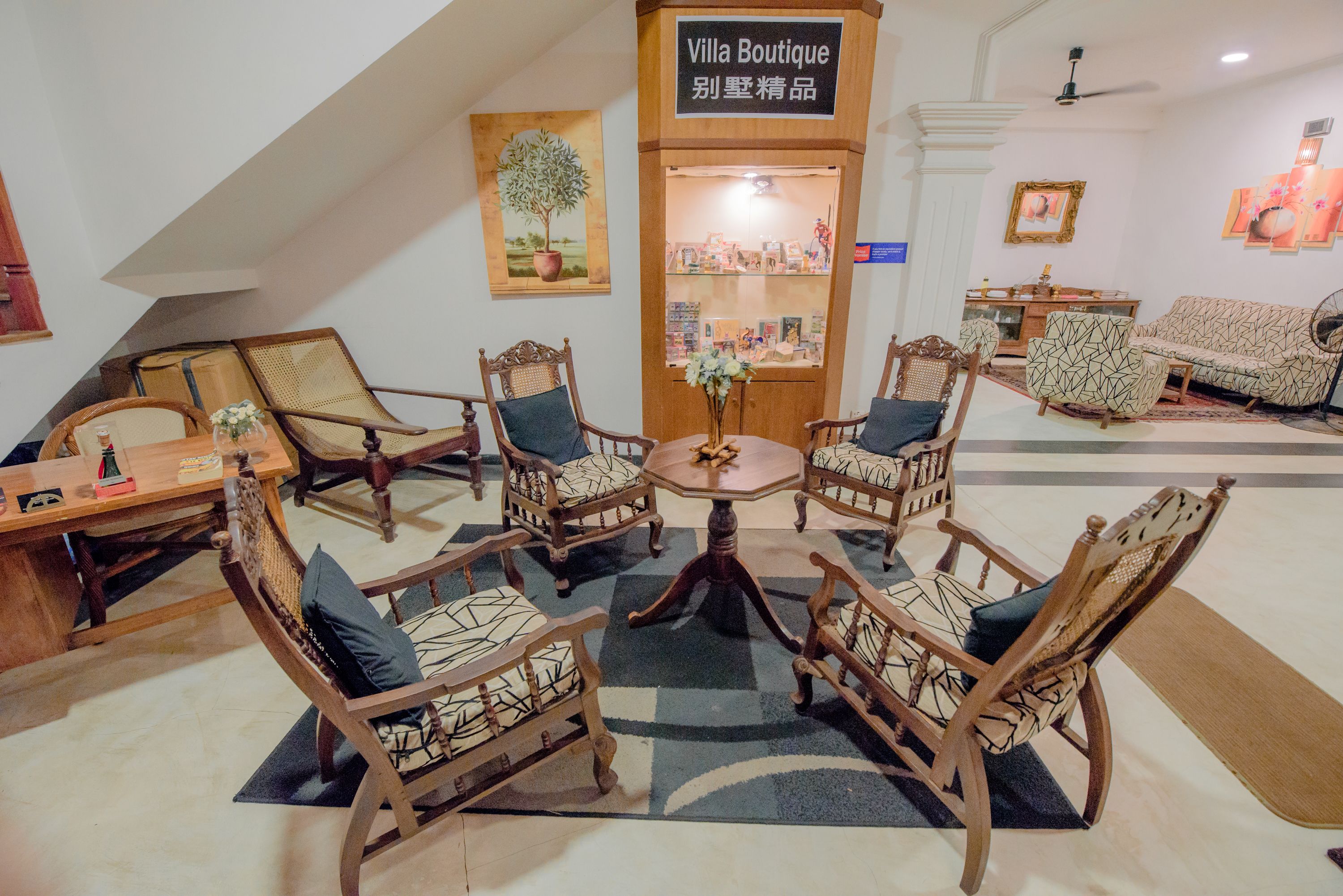 Un espace salon accueillant, avec des meubles en bois, une table centrale et un panneau indiquant « Villa Boutique ».
